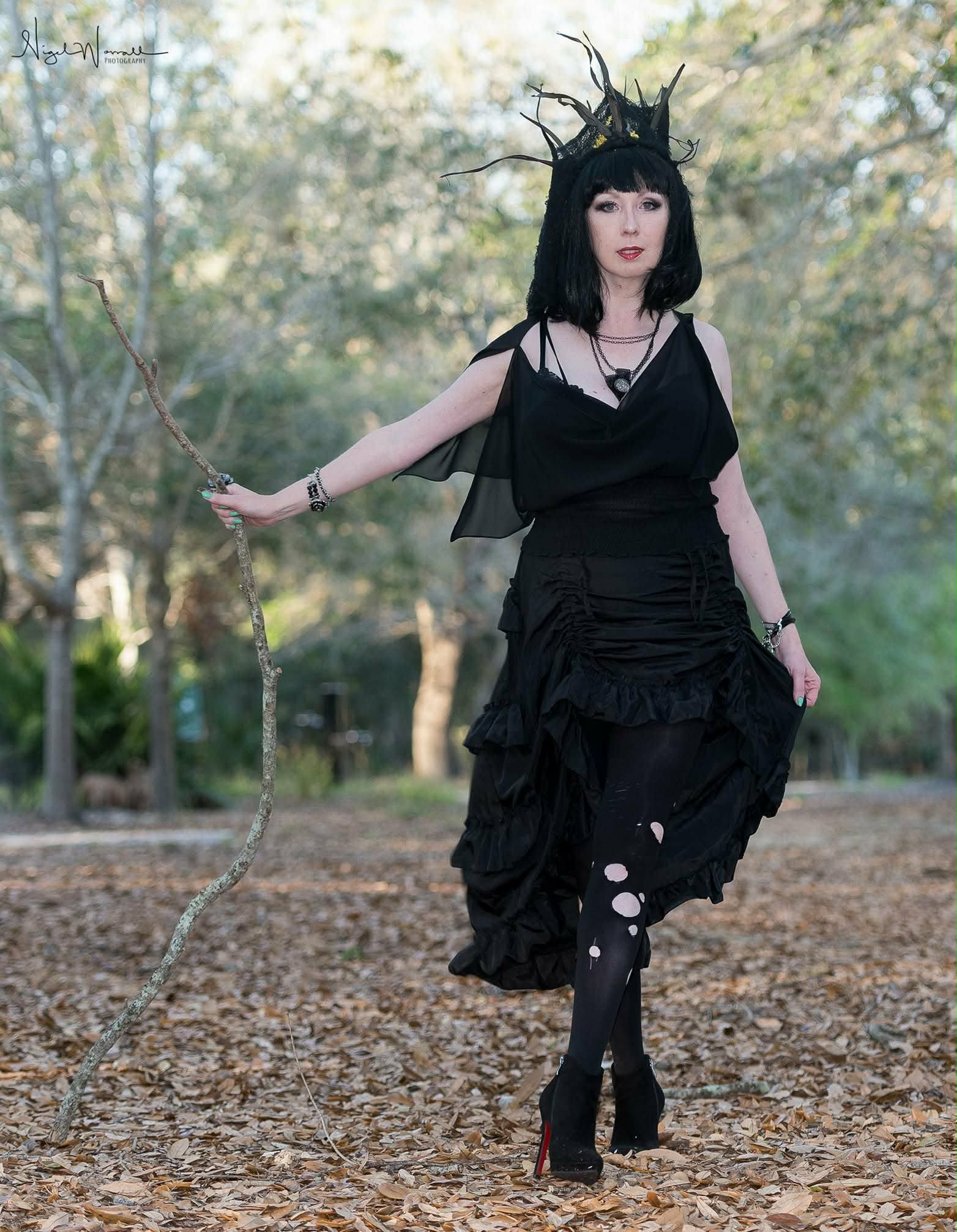 Full-length editorial portrait styled by Jenni with a sculptural black crown, layered Punk Bubble jewelry, bracelets, and spotted hosiery