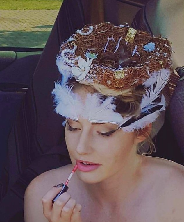 Portrait wearing a handmade bird’s-nest headpiece with white feathers and flowers