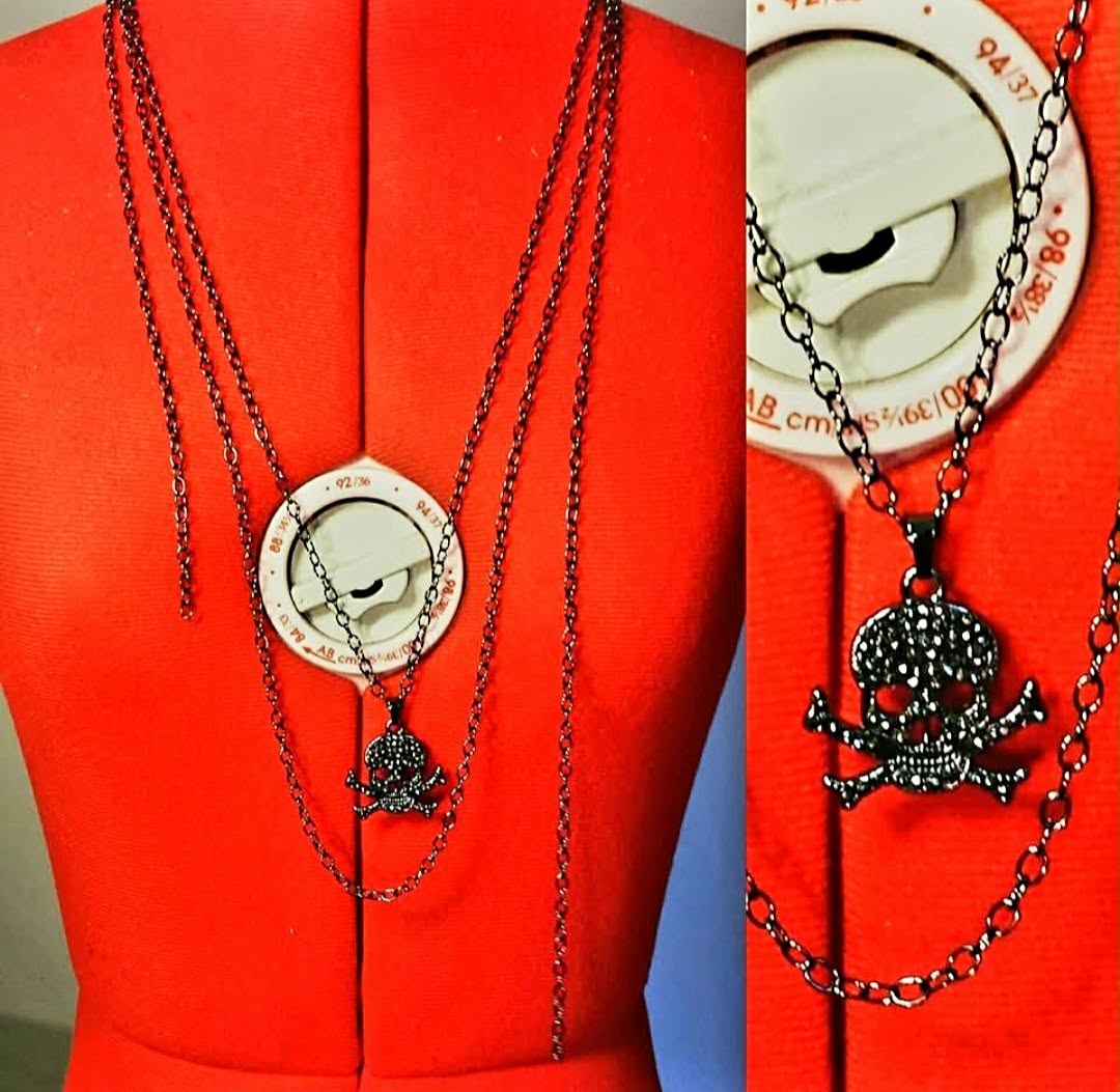 Layered necklaces with clock, skull, and floral details displayed on red forms