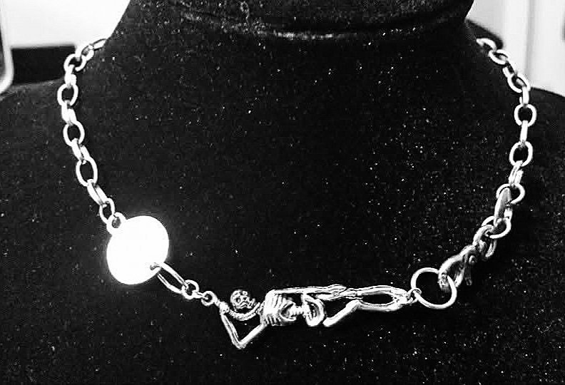 Black-and-white chain necklace with a skeletal hand centerpiece