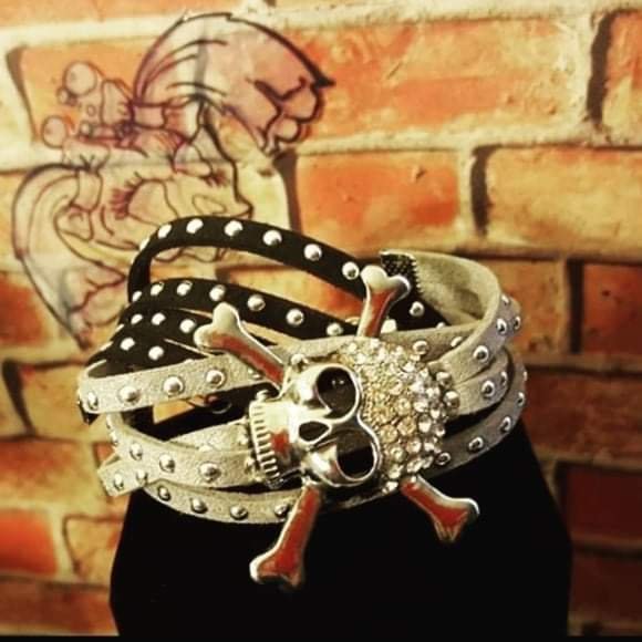 Silver and black wrap bracelet with studs, rhinestones, and a skull-and-crossbones centerpiece